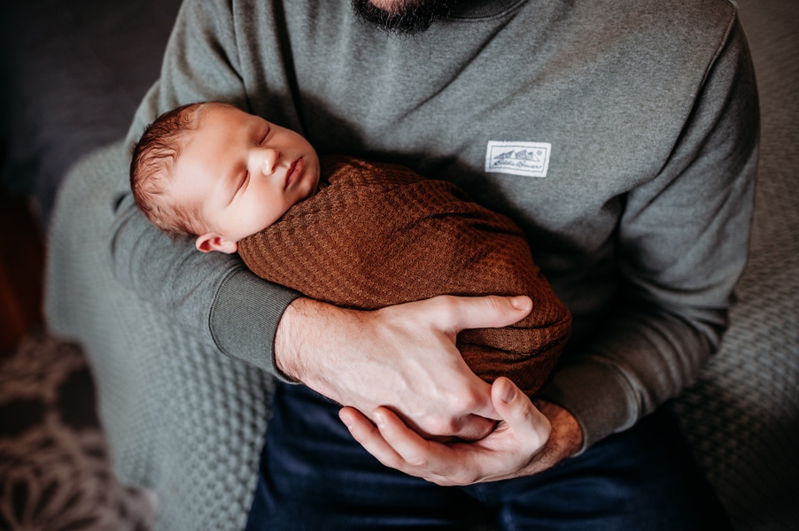 Newborn Photographer, a father holds his baby in his arms