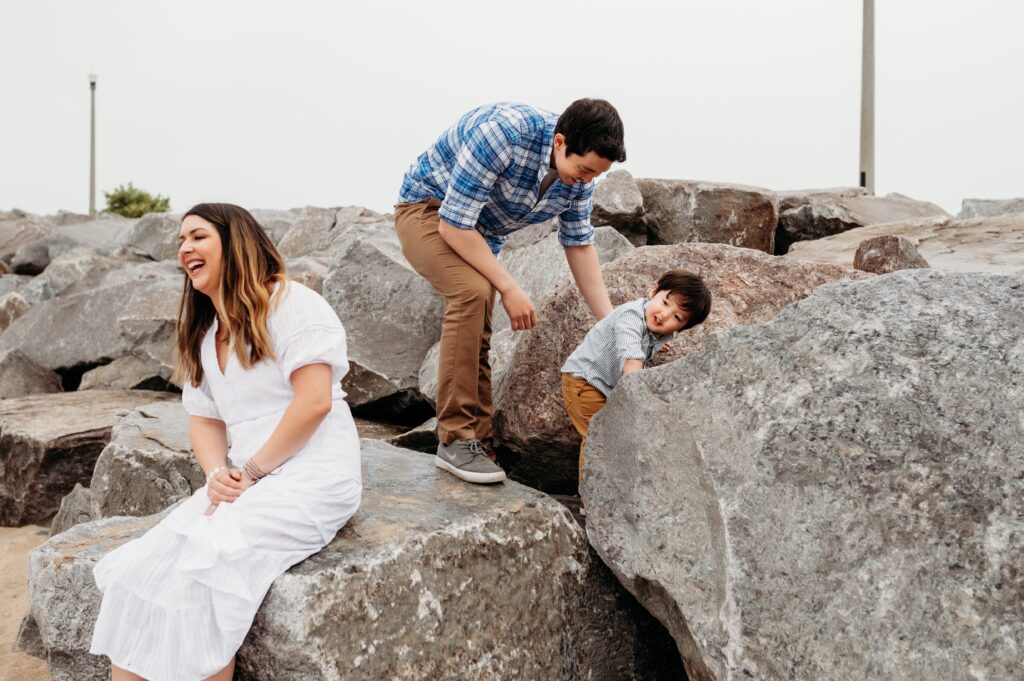 Family Photographer, a family of three plays on beach rocks