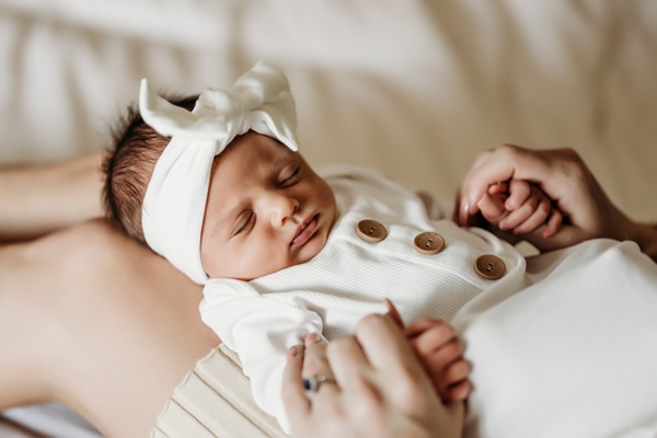 Newborn Photographer, a baby sleeps on her mother's lap