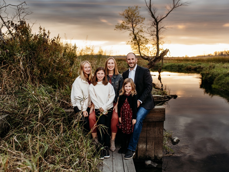 Family & Newborn Photographer, family of five standing on wooden bridge next to water