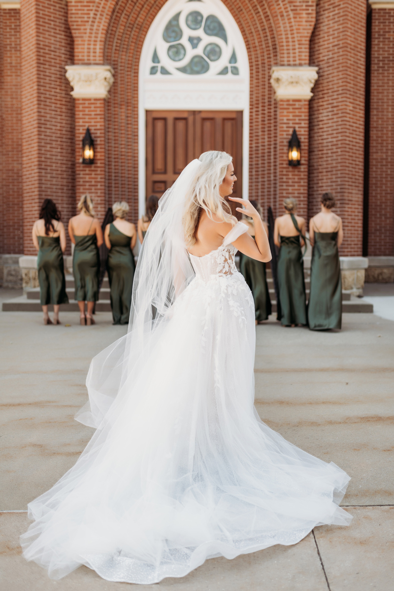 Wedding & Elopement Photography, bride standing outside of church with her bridesmaids in the background